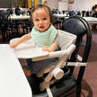 Baby using the Unilove FeedMe Booster Seat, a versatile feeding chair with adjustable height, secure harness, and removable tray.