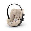 Cloud G i-Size infant car seat in beige fabric with padded harness, black shell, and curved carry handle.