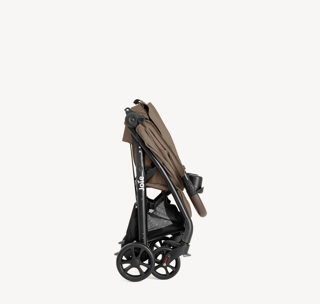 Joie Muze™ lx stroller in taupe fabric with a black frame, large wheels, storage basket and cup holder, folded compactly.