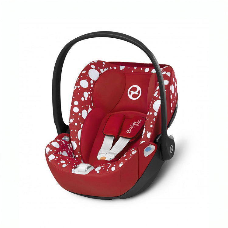 Baby car seat with red fabric, white polka dots, padded harness and black carry handle, Jeremy Scott Petticoat Cloud Z design.